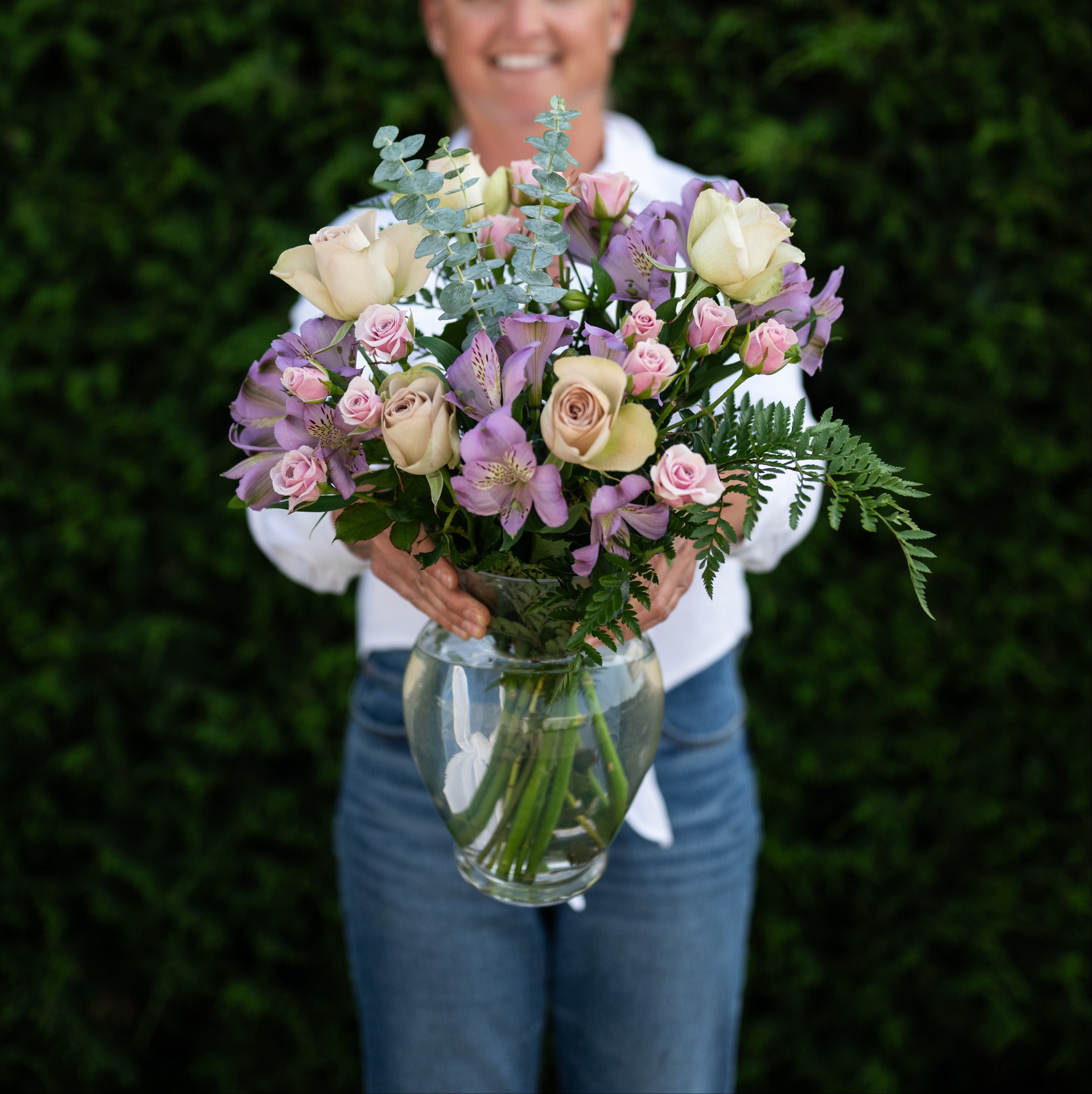 Person holding a bouquet of flowers against a green background